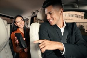Young,Woman,Showing,Smartphone,To,Taxi,Driver,In,Modern,Car